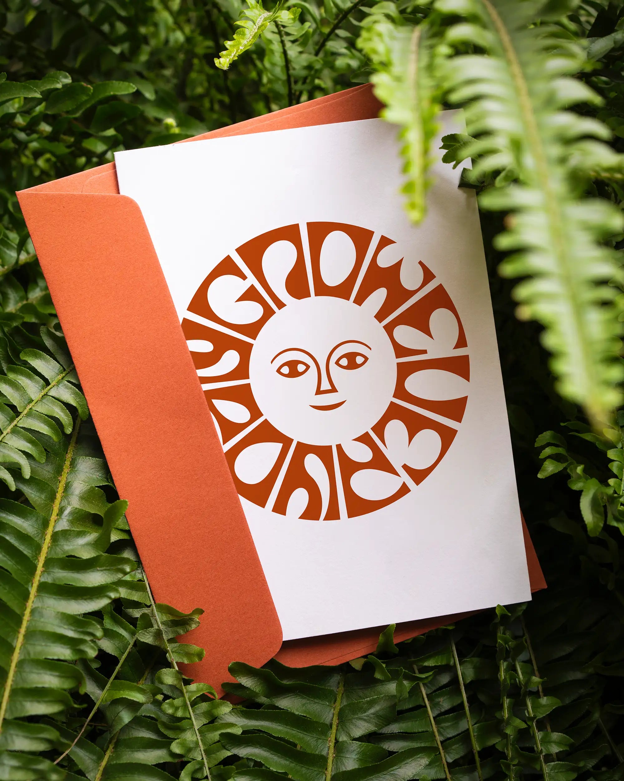Geschenkgutschein von Calienna in Wien mit dem Sonnenmotiv des "Grow Every Day" Markenzeichens, zwischen Farnblättern.