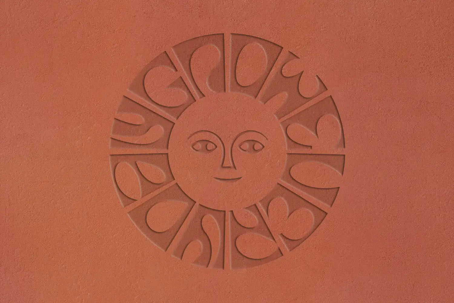 Calienna Markenzeichen in Terrakotta geprägt: stilisiertes Sonnengesicht, umgeben vom "Grow Every Day" Schriftzug.
