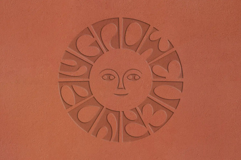 Calienna Markenzeichen in Terrakotta geprägt: stilisiertes Sonnengesicht, umgeben vom "Grow Every Day" Schriftzug.